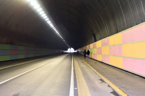Tunnel under a cliff in an italian city with people and cars passing by