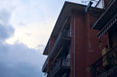 Arka plan olarak bulutlu bir gün batımı gökyüzü olan bir binanın ön cephesi.