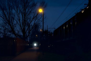 Alacakaranlıkta köprüden görünen bir parktaki setten geçen tren.