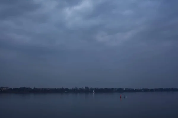 Sjön Vid Solnedgången Molnig Dag Med Ett Segelfartyg Fjärran — Stockfoto