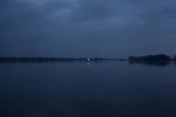 遠くにセーリング船と曇りの日の日没で湖 — ストック写真