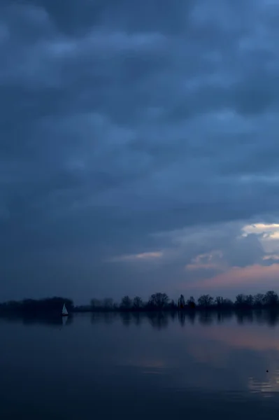 遠くにセーリング船と曇りの日の日没で湖 — ストック写真