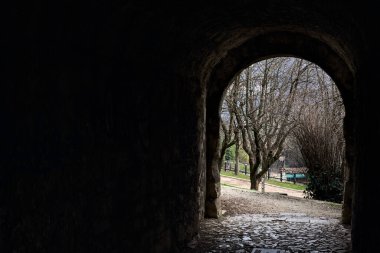 Bir kalenin sınır duvarında karanlık ve örtülü bir geçit.