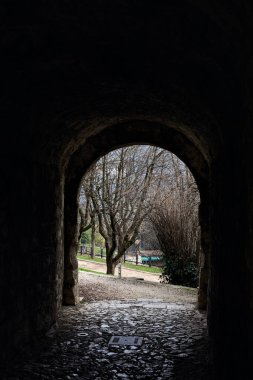 Bir kalenin sınır duvarında karanlık ve örtülü bir geçit.