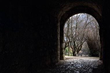 Bir kalenin sınır duvarında karanlık ve örtülü bir geçit.