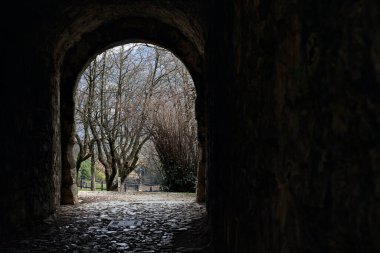 Bir kalenin sınır duvarında karanlık ve örtülü bir geçit.