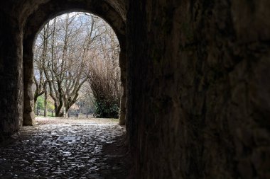 Bir kalenin sınır duvarında karanlık ve örtülü bir geçit.