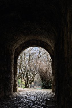 Bir kalenin sınır duvarında karanlık ve örtülü bir geçit.