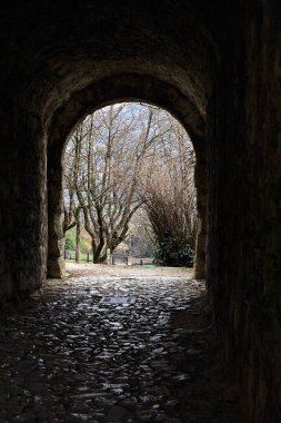 Bir kalenin sınır duvarında karanlık ve örtülü bir geçit.