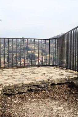 Parkta ve yamaçta arka planda binalar olan panoramik balkon.