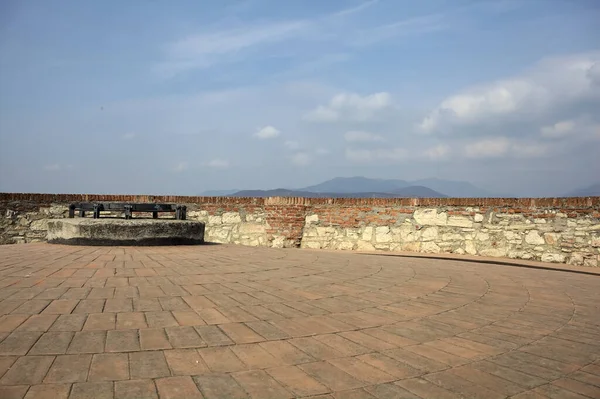 Top of a defensive tower in a castle with the sky and a city below as background