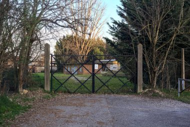 Gün batımında toprak yolun sonundaki bir fabrikaya giriş kapısı.