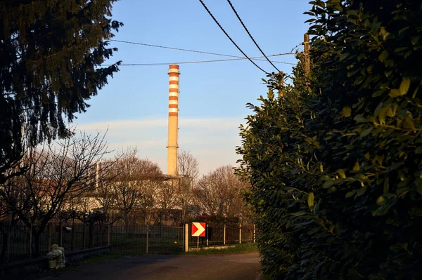 stock image Road in a village in the countryside at sunset with a smokestack in the distance