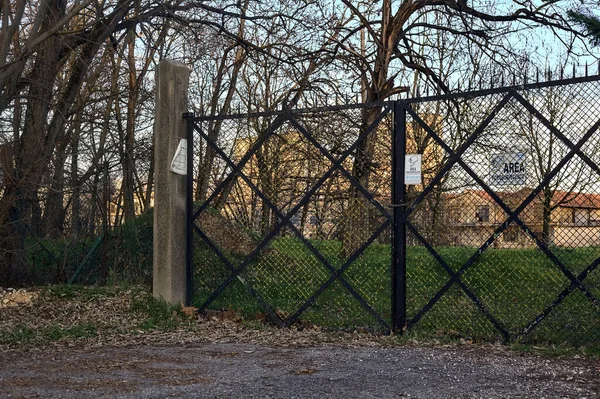 Entrance gate to a factory at the end of a dirt road at sunset