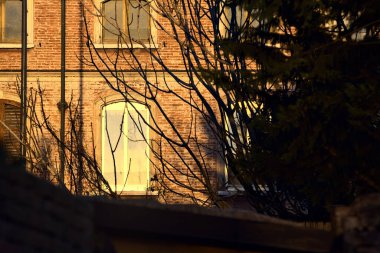 Alacakaranlıkta güneşin aydınlattığı penceresi olan bir binanın ön cephesi