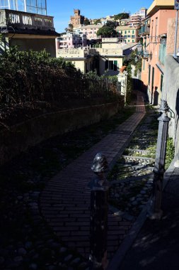 Güneşli bir günde, deniz kenarında bir tepede patika bir sokak.