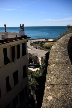 Güneşli bir günde deniz ve kıyı binalarla çevrili.