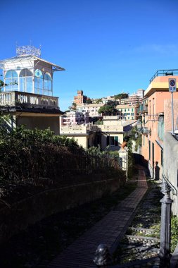 Güneşli bir günde, deniz kenarında bir tepede patika bir sokak.
