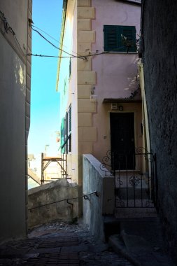 Sahildeki bir kasabanın gölgesinde kaldırımlı bir ara sokağın köşesinde.