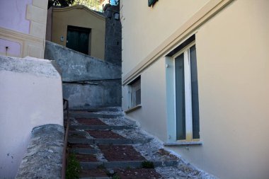 Sahildeki bir kasabanın gölgesinde kaldırımlı bir ara sokağın köşesinde.