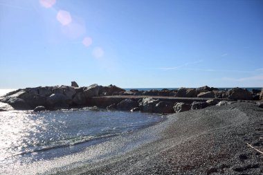 Kışın güneşli bir günde deniz ufka doğru uzanırken sahil ve dalgalı sular.