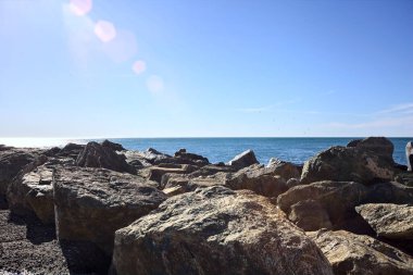 Dalgakıran tarafından çerçevelenmiş güneşli bir günde deniz ufka doğru uzanıyor.