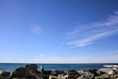 Dalgakıran tarafından çerçevelenmiş güneşli bir günde deniz ufka doğru uzanıyor.