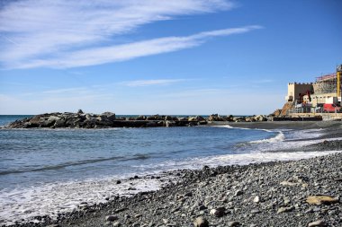 Kışın güneşli bir günde deniz ufka doğru uzanırken sahil ve dalgalı sular.