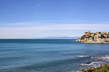 Açık bir günde, uzak bir mesafeden denize uzanan tarihi binalarla dolu bir uçurum.