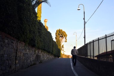 Alacakaranlıkta görülen köşk çitleriyle çevrili bir tepede.