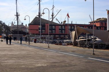 Güneşli bir günde rıhtımda teknelerle dolu bir bulvarda.