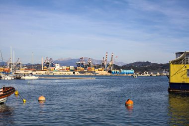 Gün batımında bir limanda nakliye ve sanayi kompleksi uzaklardan görülüyor.
