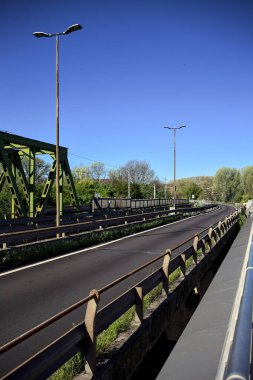 Güneşli bir günde nehri geçen bir yol ve tren yolu olan bir köprü.