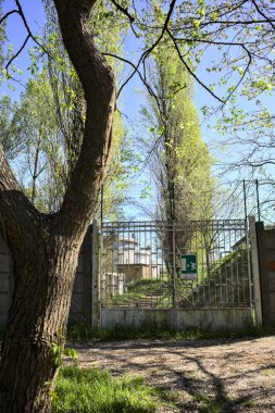 Bir parktaki yolun kenarındaki fabrikanın beton bir sınır duvarındaki kapı.