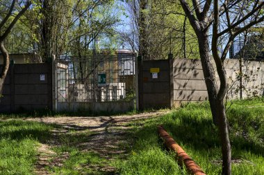 Bir parktaki yolun kenarındaki fabrikanın beton bir sınır duvarındaki kapı.