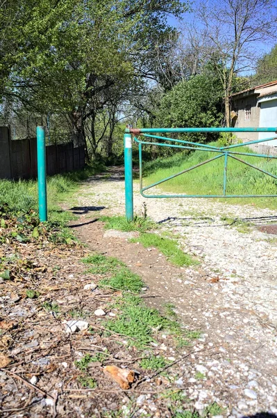 stock image Dirt path in a forest next to a group of houses with a bar blocking the way on a sunny day