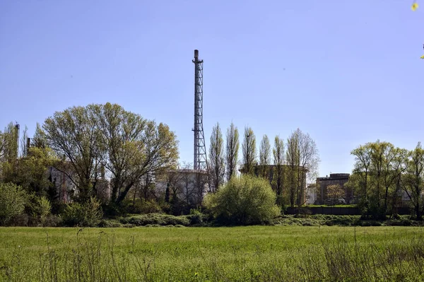 Meadow in a forest and an industrial complex hidden behind trees on a sunny day in the italian countryside in spring