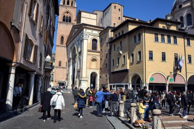 Güneşli bir günde İtalyan kasabasında gezen insanlarla dolu bir meydan.