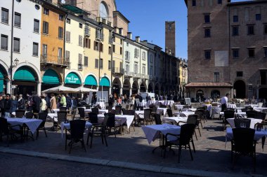 Güneşli bir günde İtalyan kasabasında gezen insanlarla dolu bir meydan.