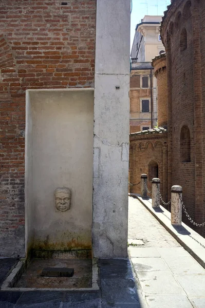 stock image Fountain shaped as a face in a palace next to an alley in an italian town on a sunny day