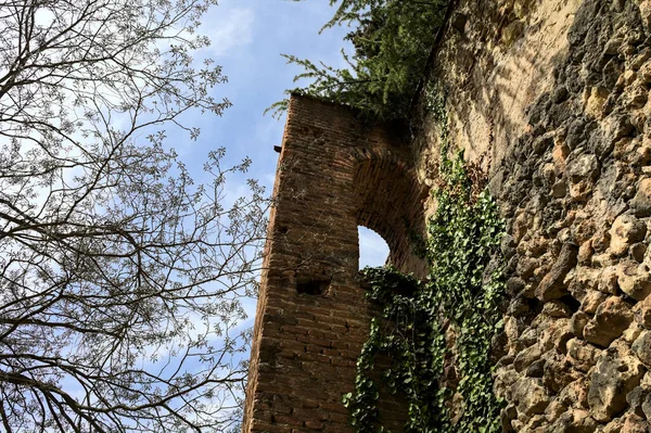 Tower of a boundary wall next to a dirt path in a park on a hill