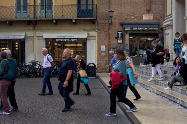 Meydanda bir merdivenin yanında turistler geçerken.