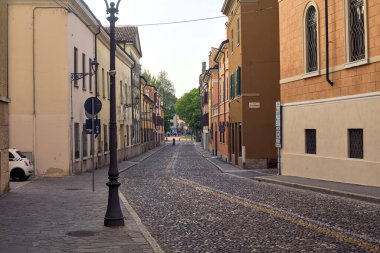 Günbatımında bir İtalyan kasabasında parka giden kaldırımdan görünen kaldırımlı bir cadde.