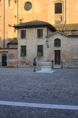 Kuyusu olan bir meydan ve gün batımında yanında uzanan bir adam.