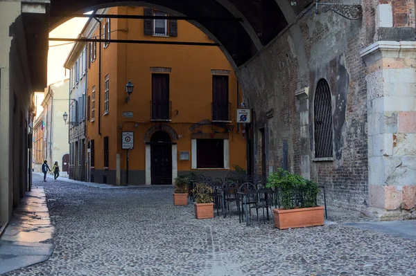 イタリアの町のテーブルと椅子のある宮殿の下の屋根付きの路地 — ストック写真