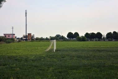 İtalya 'nın kırsal kesimlerinde bulutlu bir günde, bir tarlada gol ve uzakta bir yol ile futbol sahası