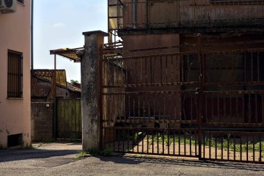 Terk edilmiş depo, İtalya 'nın kırsal kesimlerinde güneşli bir günde bir ara sokakta kapılar tarafından kapatılmış.