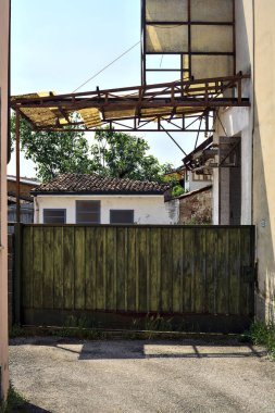 Terk edilmiş depo, İtalya 'nın kırsal kesimlerinde güneşli bir günde bir ara sokakta kapılar tarafından kapatılmış.