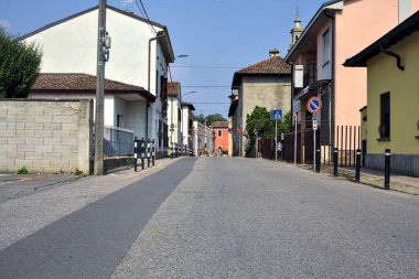 İtalya 'nın kırsal kesimindeki bir köyde güneşli bir günde sonunda bir kilise olan evlerle çevrili bir yol.