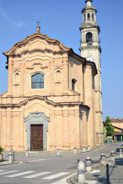İtalya 'nın kırsal kesimindeki bir köyde güneşli bir günde bir kilise ve bir depo önünde meydan.